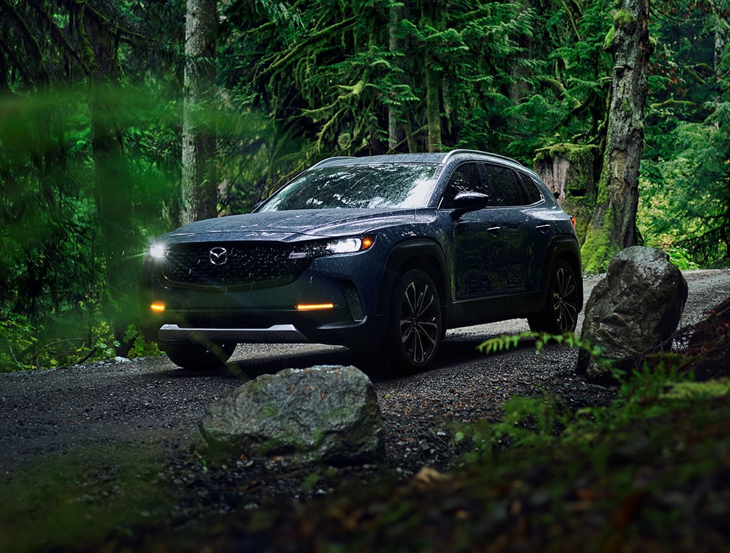 Black Mazda CX-50 driving in the woods